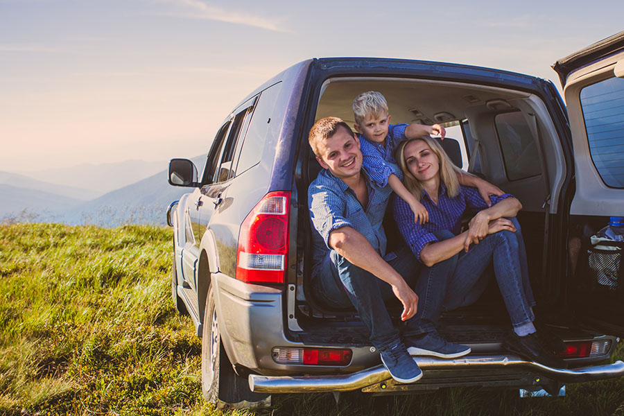 Blog - Young Parents With Son Sitting In Open Trunk Of Jeep In The Mountains